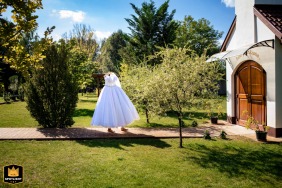   Sunlight bathes the bride as she walks alone in a hotel park in Budapest, Hungary, her dress alight and the atmosphere serene before the celebrations begin.